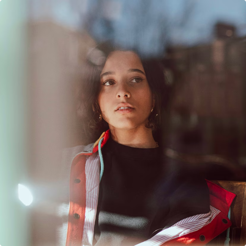 Young woman looking out a window, contemplative.
